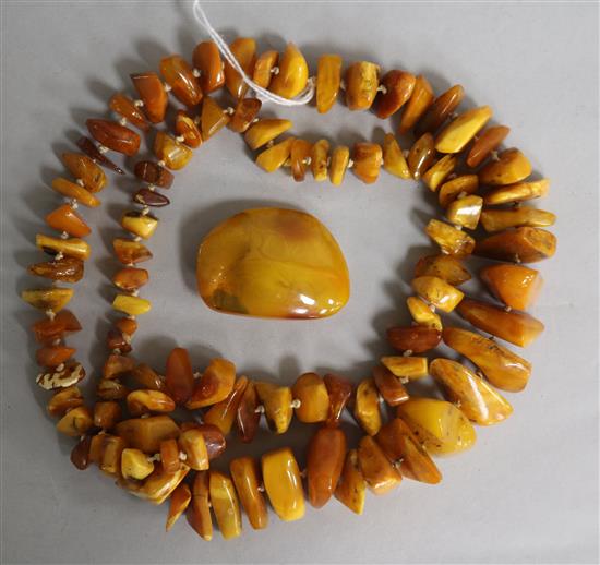 A single strand jagged amber necklace and an amber brooch, gross weight 104 grams, necklace 86cm.